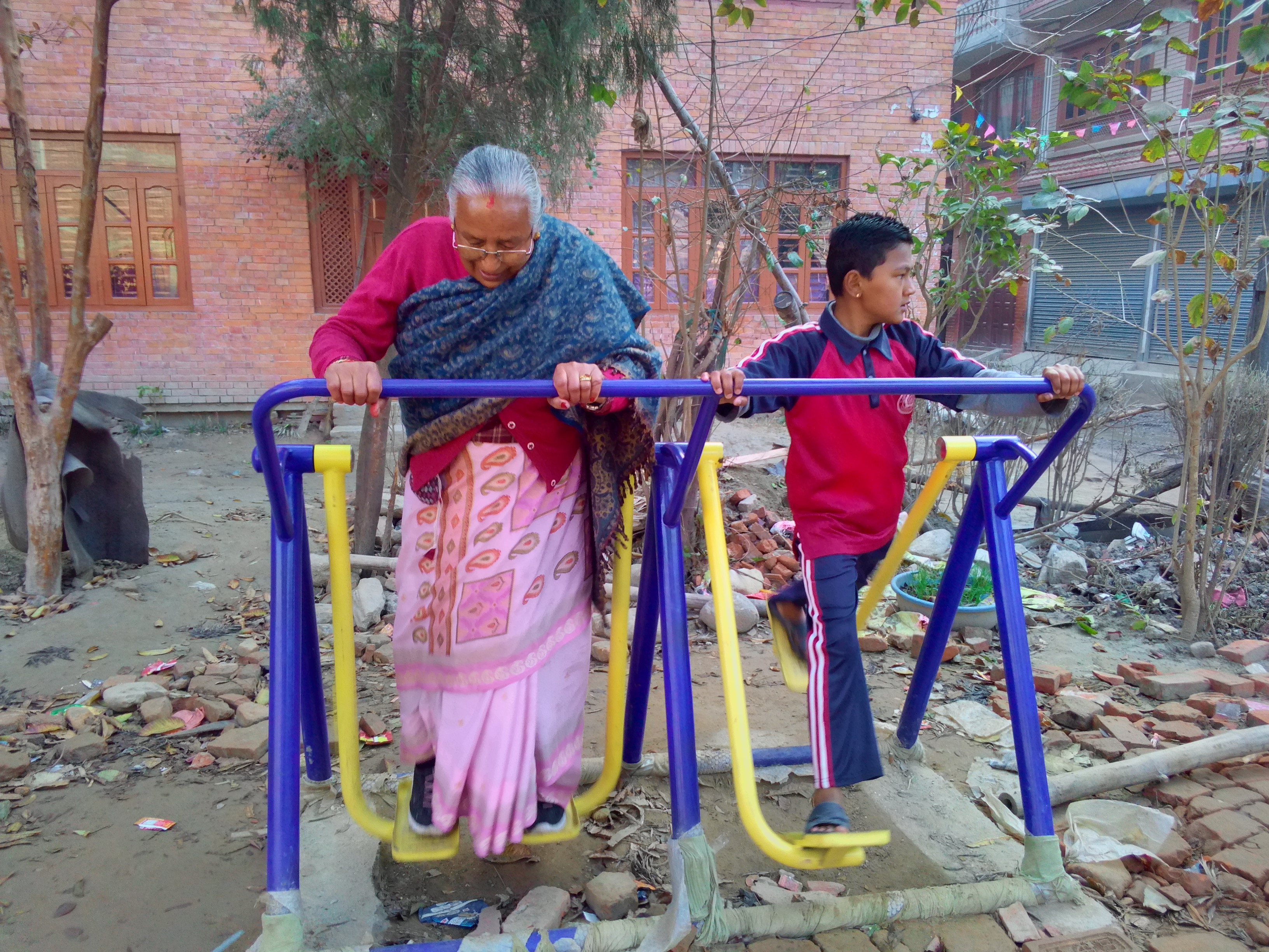 भक्तपुर, कमलविनायकमा नगरपालिकाले राखेको उपकरणमा बिहीबार व्यायाम गर्दै सीतालक्ष्मी प्रजापति र उनका नाति। तस्बिर: सबिना श्रेष्ठ/सेतोपाटी